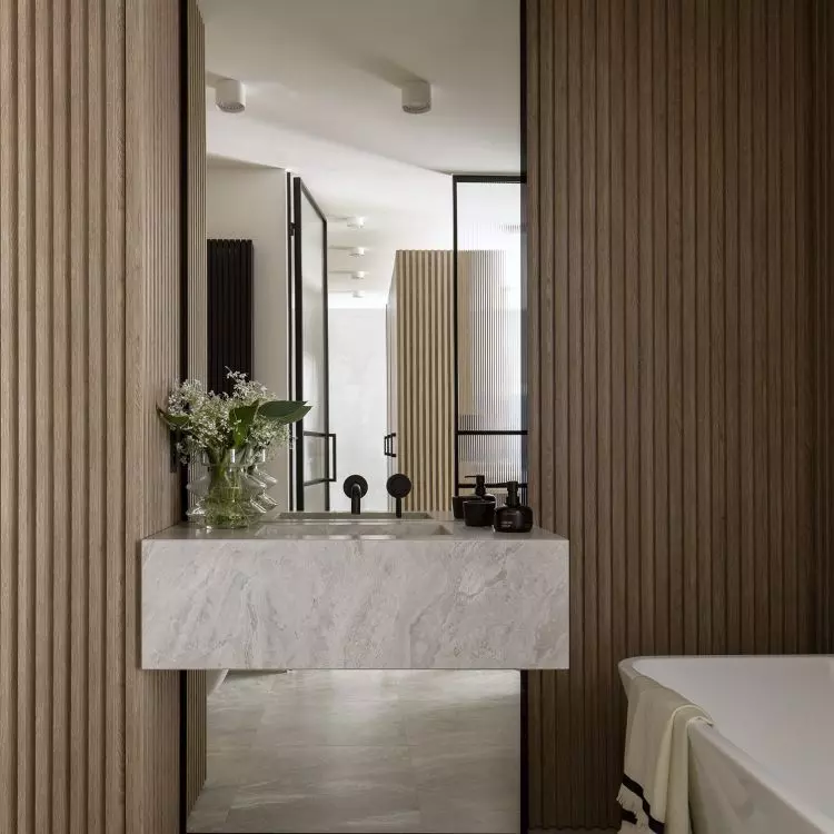 The stone washbasin relates in design to the tiles on the wall