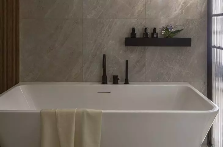 The glass-enclosed bathroom features a freestanding bathtub