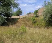 Southern tip of Ostrów Tumski, left bank of the relief canal; excavations visible, behind them the chimney of the Old Gasworks