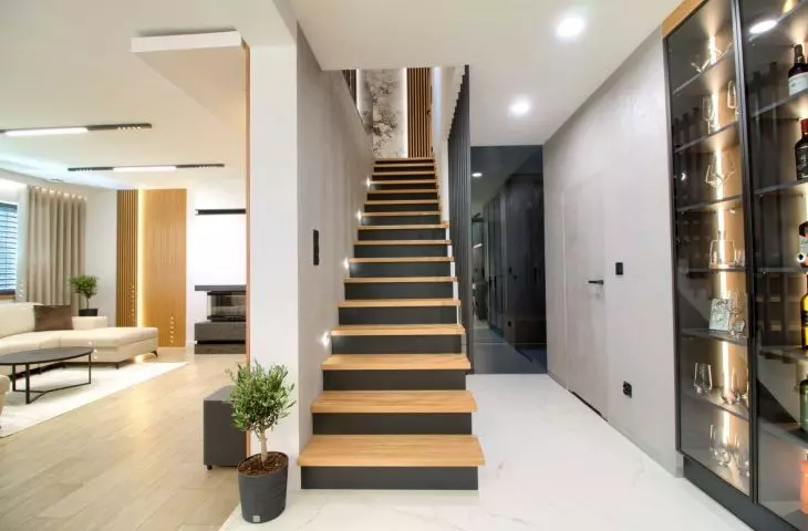 The living room is separated from the kitchen by an elegant staircase
