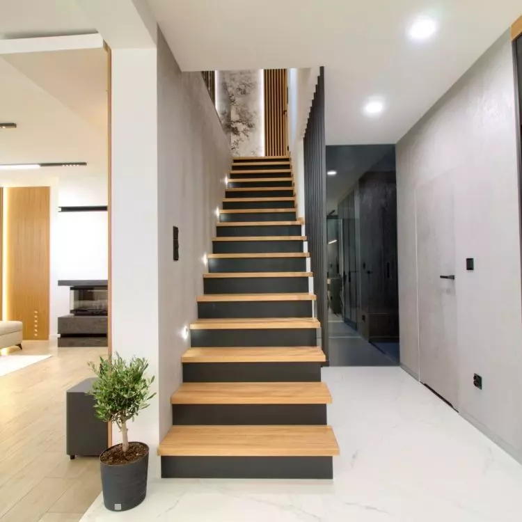 The living room is separated from the kitchen by an elegant staircase