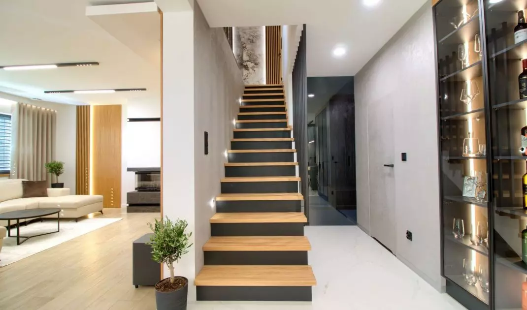 The living room is separated from the kitchen by an elegant staircase