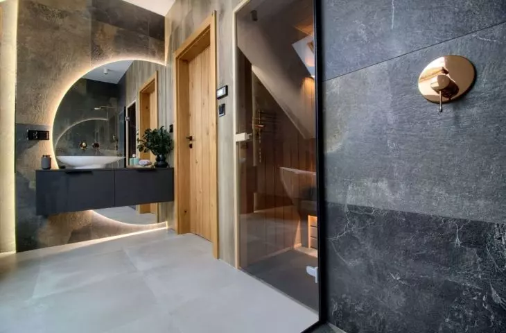 Behind the washbasin is a large illuminated mirror