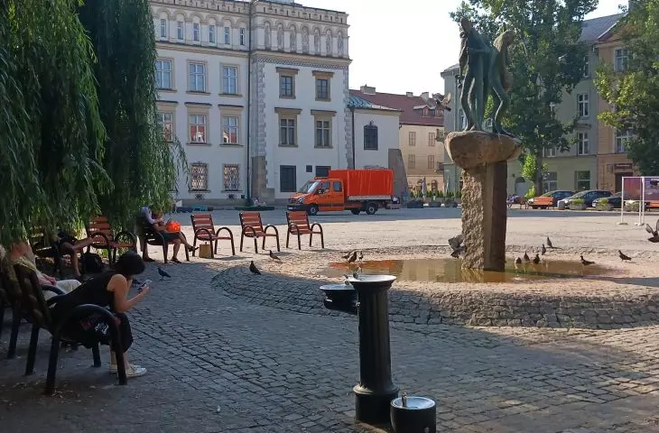 obok fontanny i drzew  dostawiono ławki i krzesła miejskie 