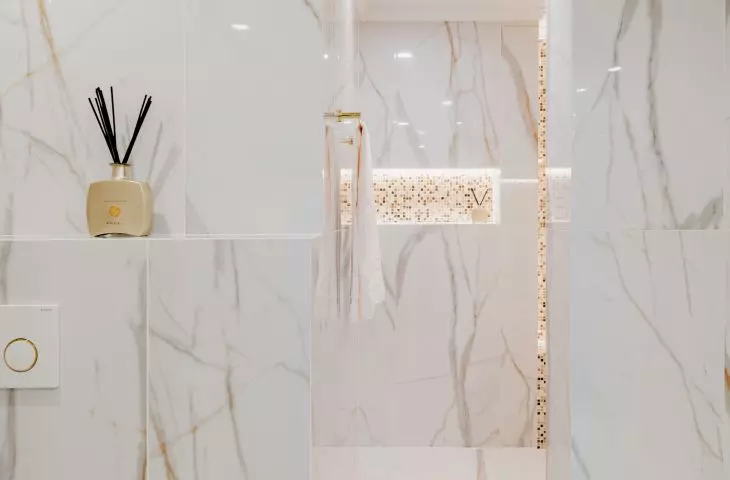 The walls and floor of the bathroom were tiled with large-format tiles with a marble pattern