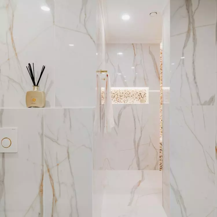 The walls and floor of the bathroom were tiled with large-format tiles with a marble pattern