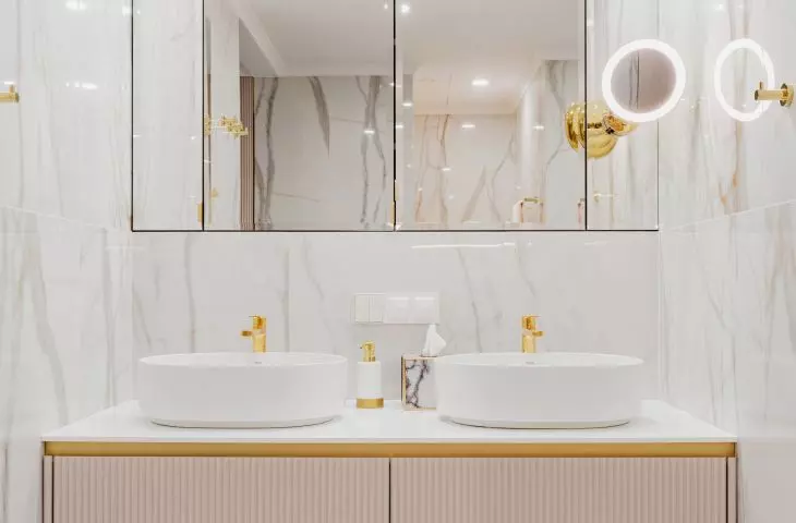 Two washbasins stand on a cabinet with a fluted front