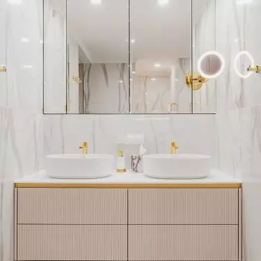 Two washbasins stand on a cabinet with a fluted front
