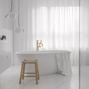 The free-standing bathtub is complemented by a gold faucet