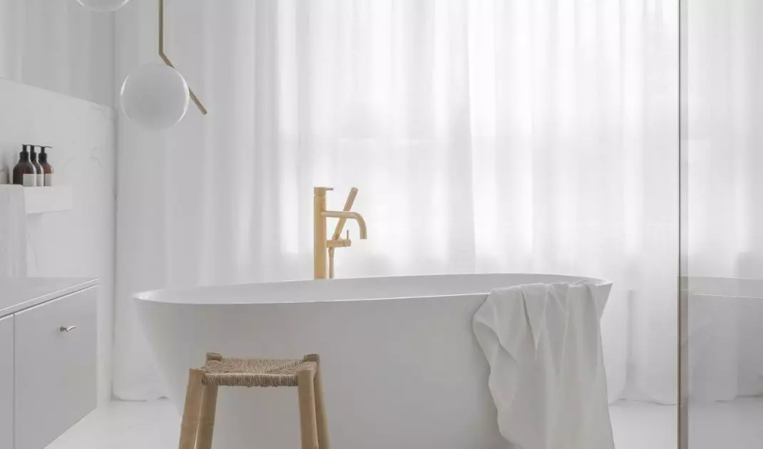 The free-standing bathtub is complemented by a gold faucet