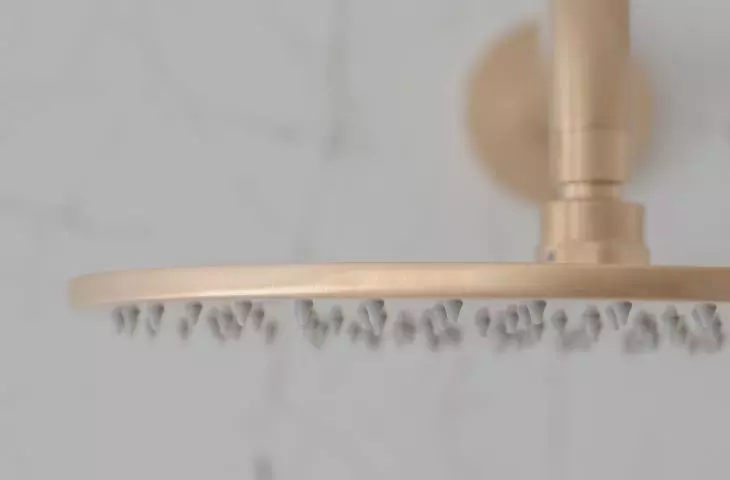 In the shower there is a golden rain shower head