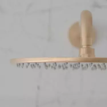In the shower there is a golden rain shower head