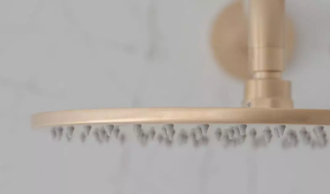 In the shower there is a golden rain shower head