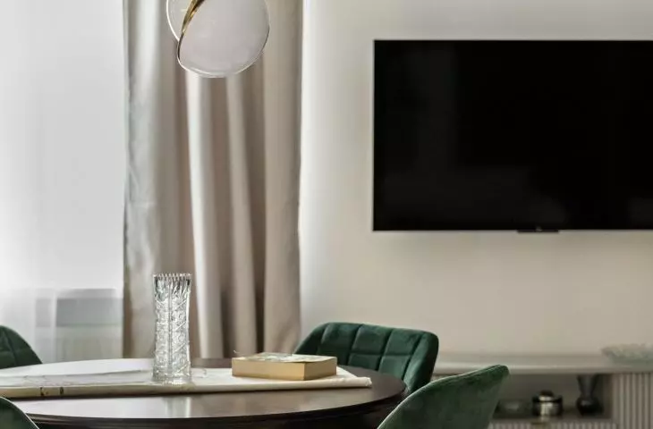 The dining room is formed by a round table and upholstered chairs in a shade of green