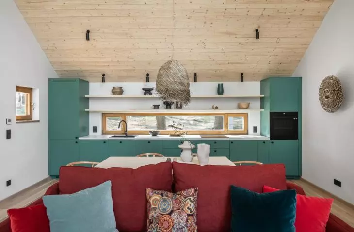 Green kitchen cabinet fronts and a red sofa are strong color accents