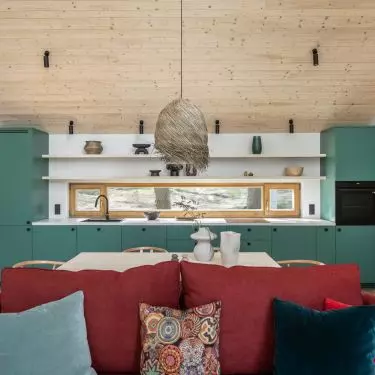Green kitchen cabinet fronts and a red sofa are strong color accents