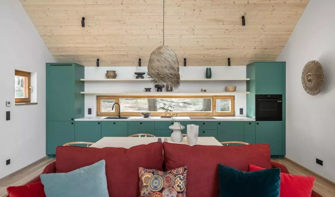 Green kitchen cabinet fronts and a red sofa are strong color accents