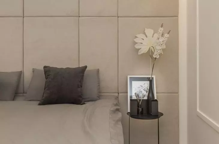 The wall behind the bed was decorated with upholstered panels
