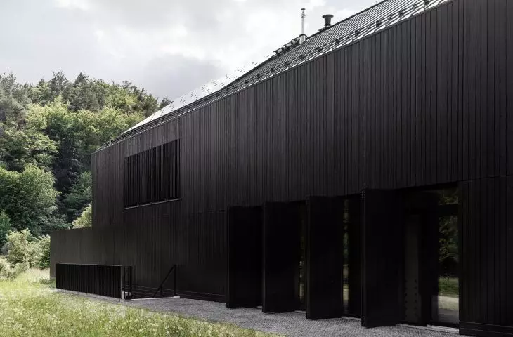 Black facade cladding allows the block to blend in with the forest surroundings