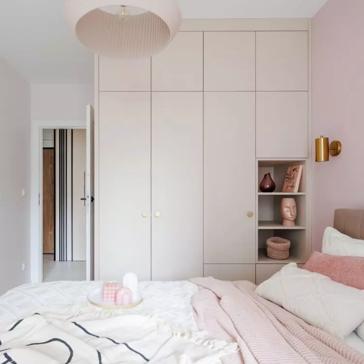 A pink lamp with a crinkle shade hangs over the bed
