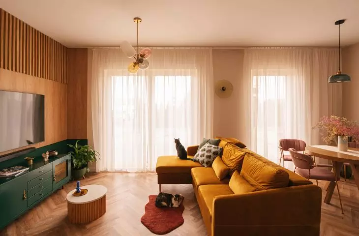 Mustard sofa connects the living room area with the kitchen