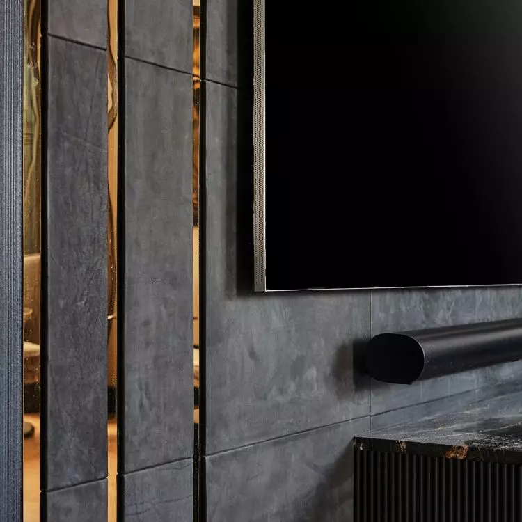 The TV wall was upholstered with black leather panels