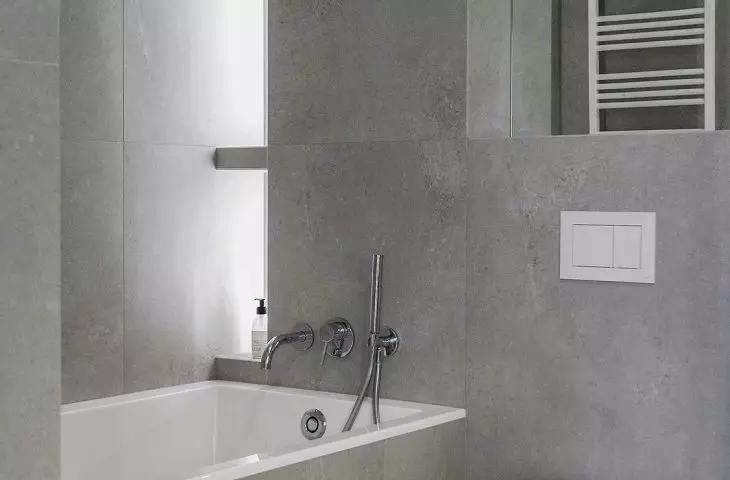 On the wall behind the bath is an illuminated bookcase