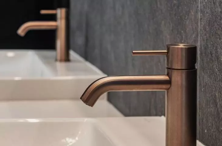 Copper faucets contrast with the anthracite background