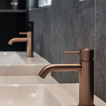 Copper faucets contrast with the anthracite background
