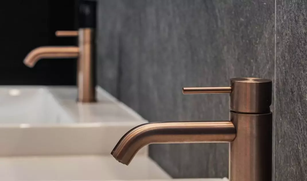 Copper faucets contrast with the anthracite background