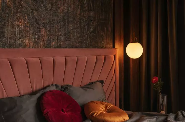 Bed in shade of dirty pink conquers warm tones of wallpaper