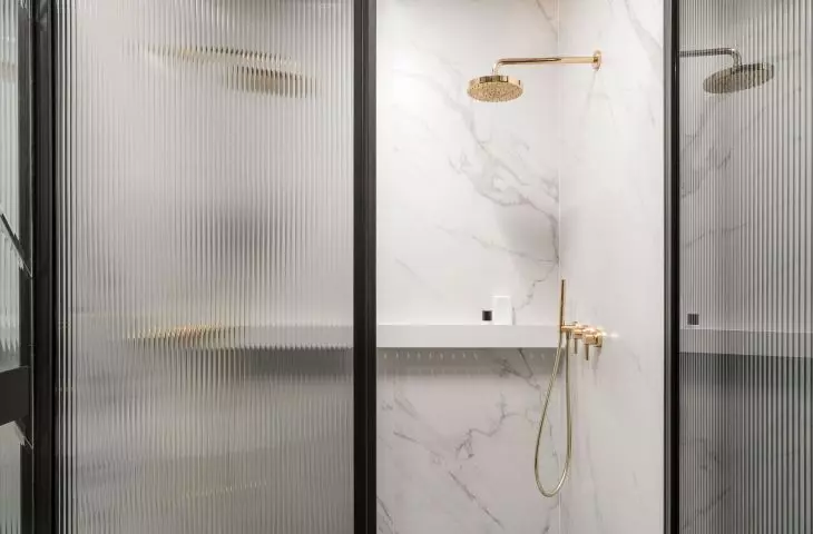 The shower hides behind a fluted glass door