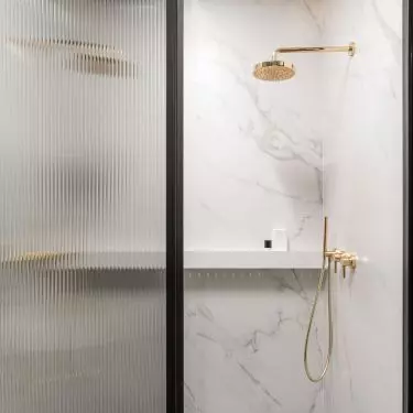 The shower hides behind a fluted glass door