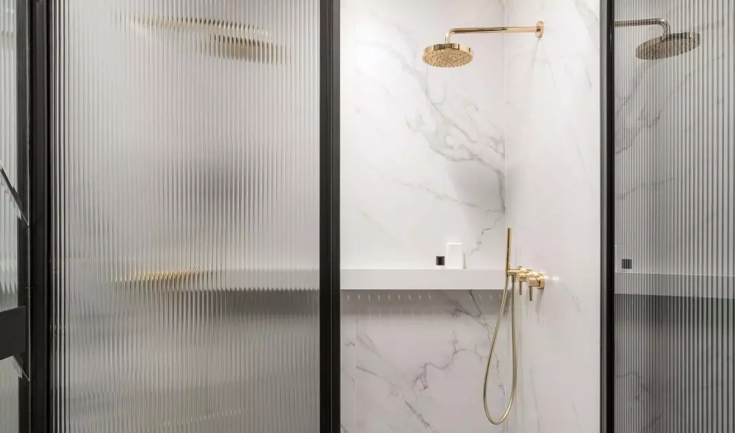The shower hides behind a fluted glass door