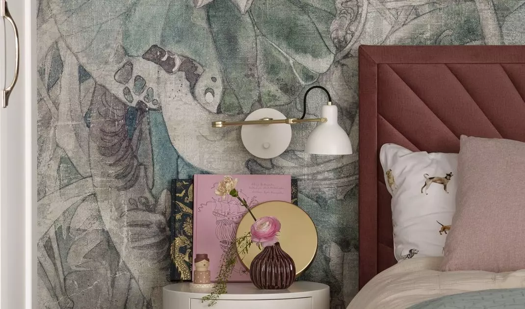 The wall behind the bed is decorated with wallpaper in pastel flowers