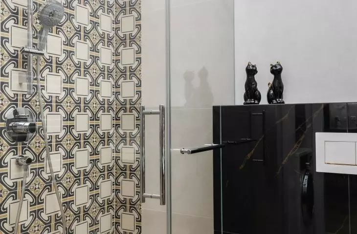 The shower wall is covered with decorative tiles