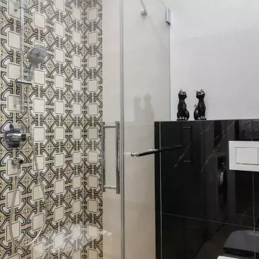 The shower wall is covered with decorative tiles