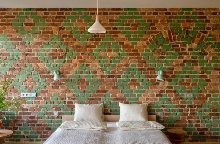 The wall in the bedroom is decorated with bricks with green decoration