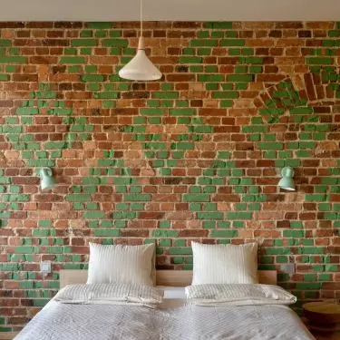 The wall in the bedroom is decorated with bricks with green decoration