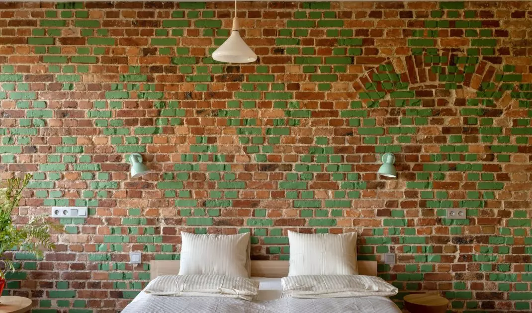 The wall in the bedroom is decorated with bricks with green decoration