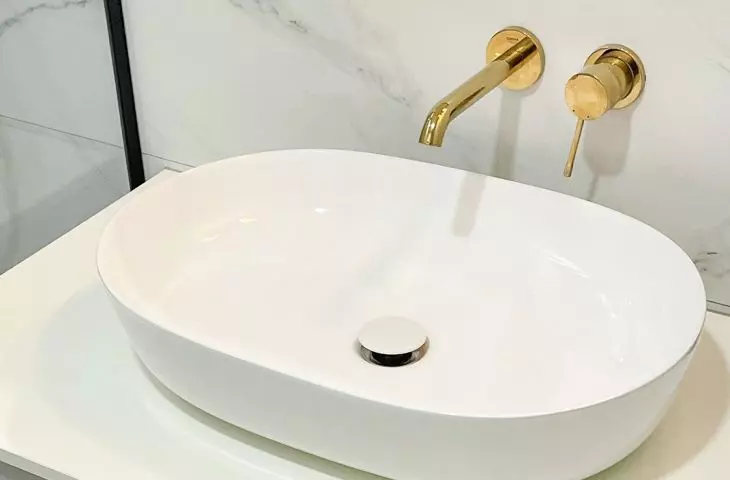The white cabinet is decorated with gold handles  
