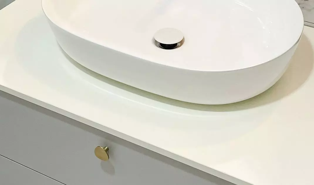 The white cabinet is decorated with gold handles  