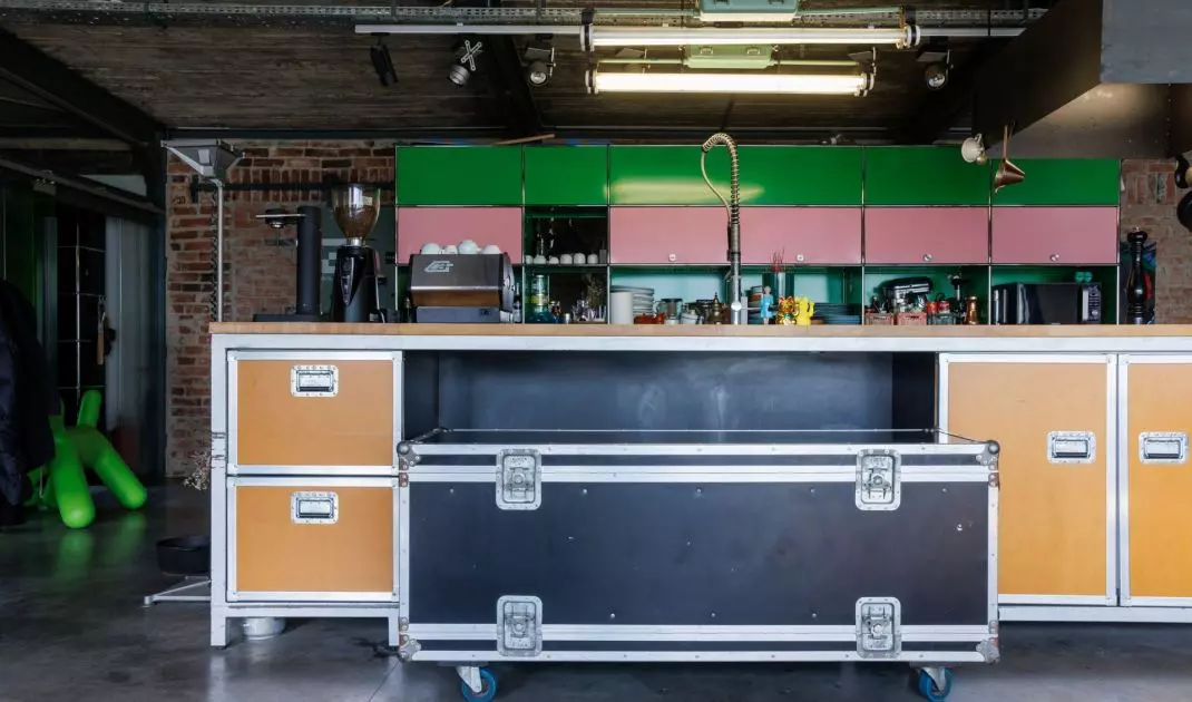 The green-pink kitchen design is complemented by a yellow island