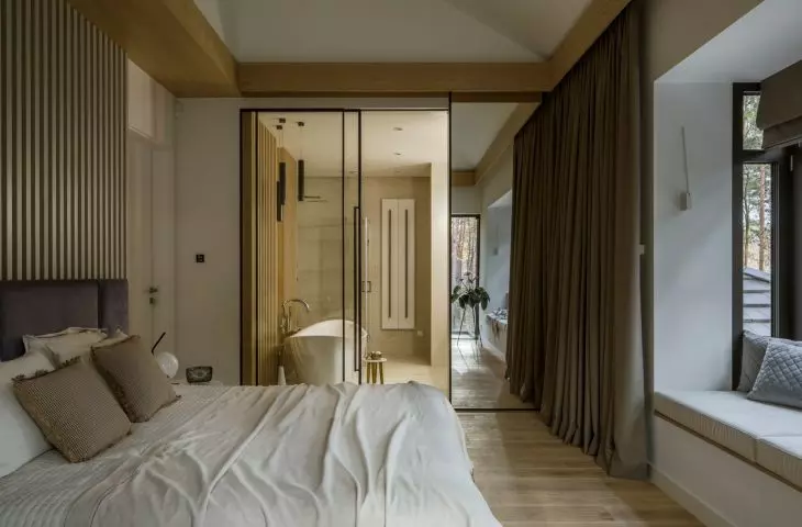 A glass wall separates the bedroom from the bathroom