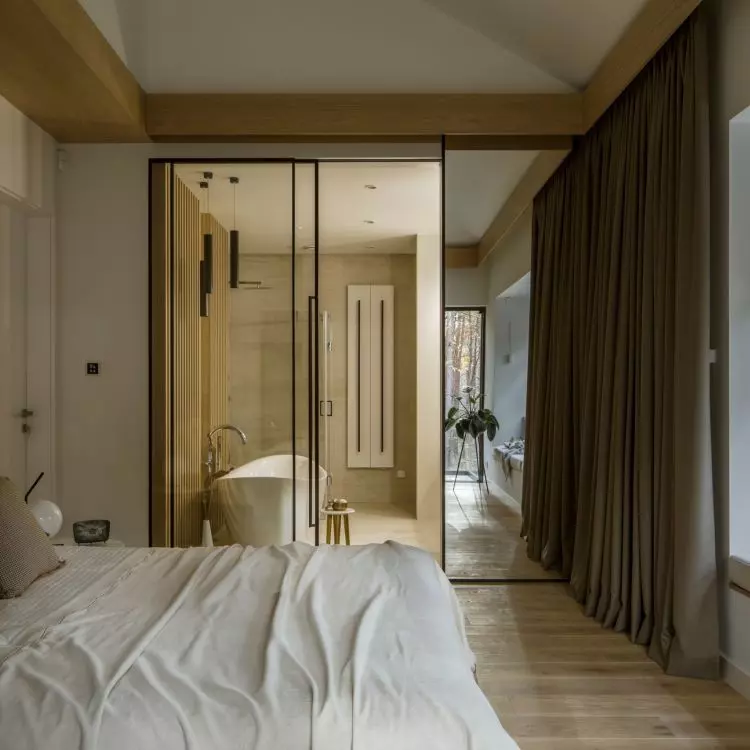 A glass wall separates the bedroom from the bathroom