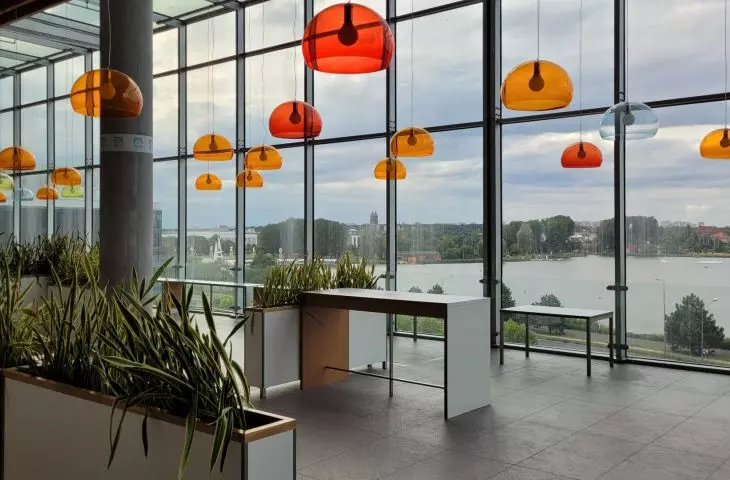 CH Malta w Poznaniu — opustoszały food court z widokiem na jezioro Malta i panoramę miasta z katedrą  