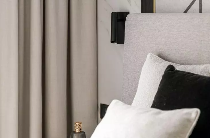 Structural lamps and geometric decorations on the wall behind the bed add dynamism to the arrangement