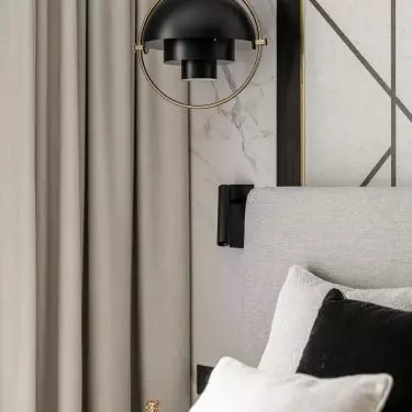 Structural lamps and geometric decorations on the wall behind the bed add dynamism to the arrangement