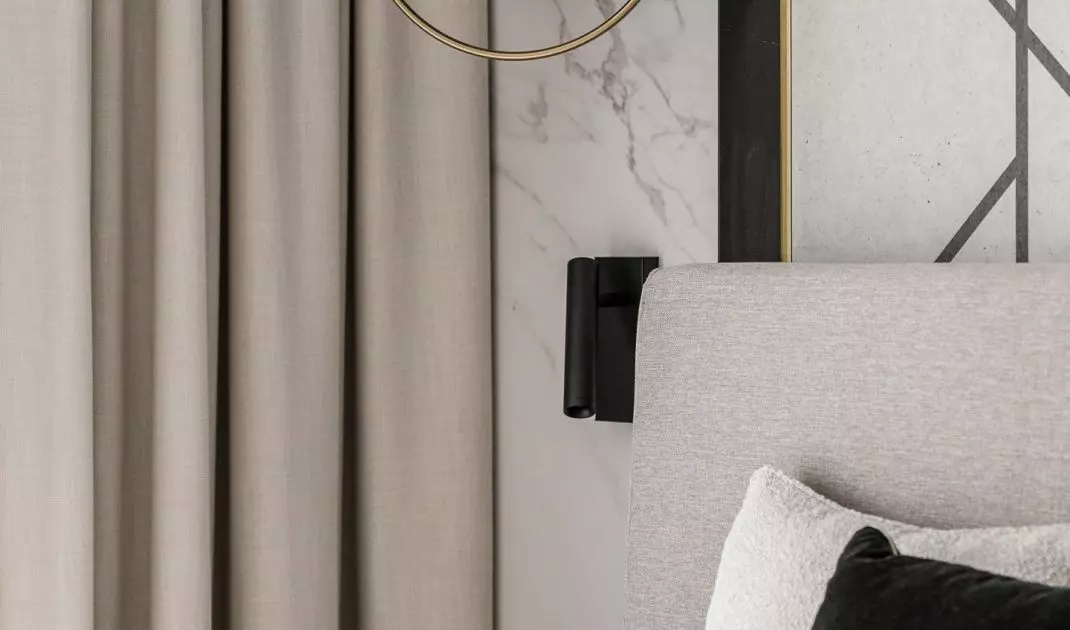 Structural lamps and geometric decorations on the wall behind the bed add dynamism to the arrangement