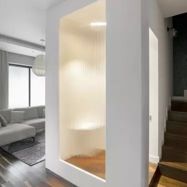 The bathroom is separated from the living room by a fluted glass pane